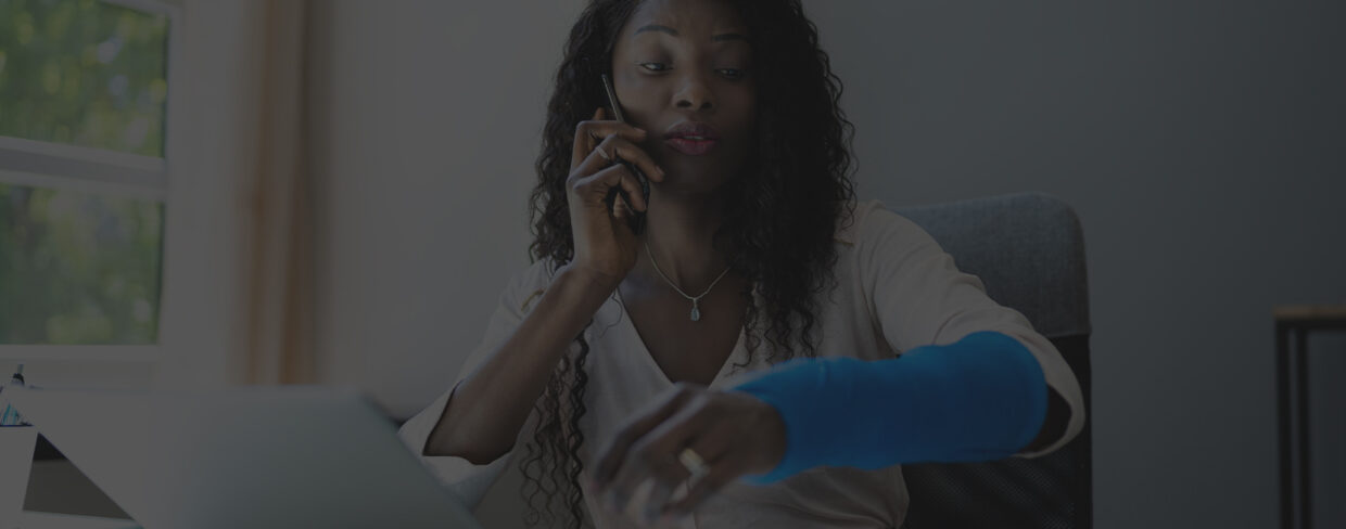 Woman on phone discussing workers' comp claim while checking time