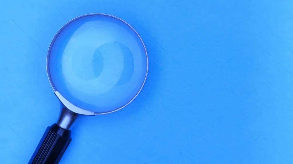 Magnifying glass on blue background representing healthcare data analysis